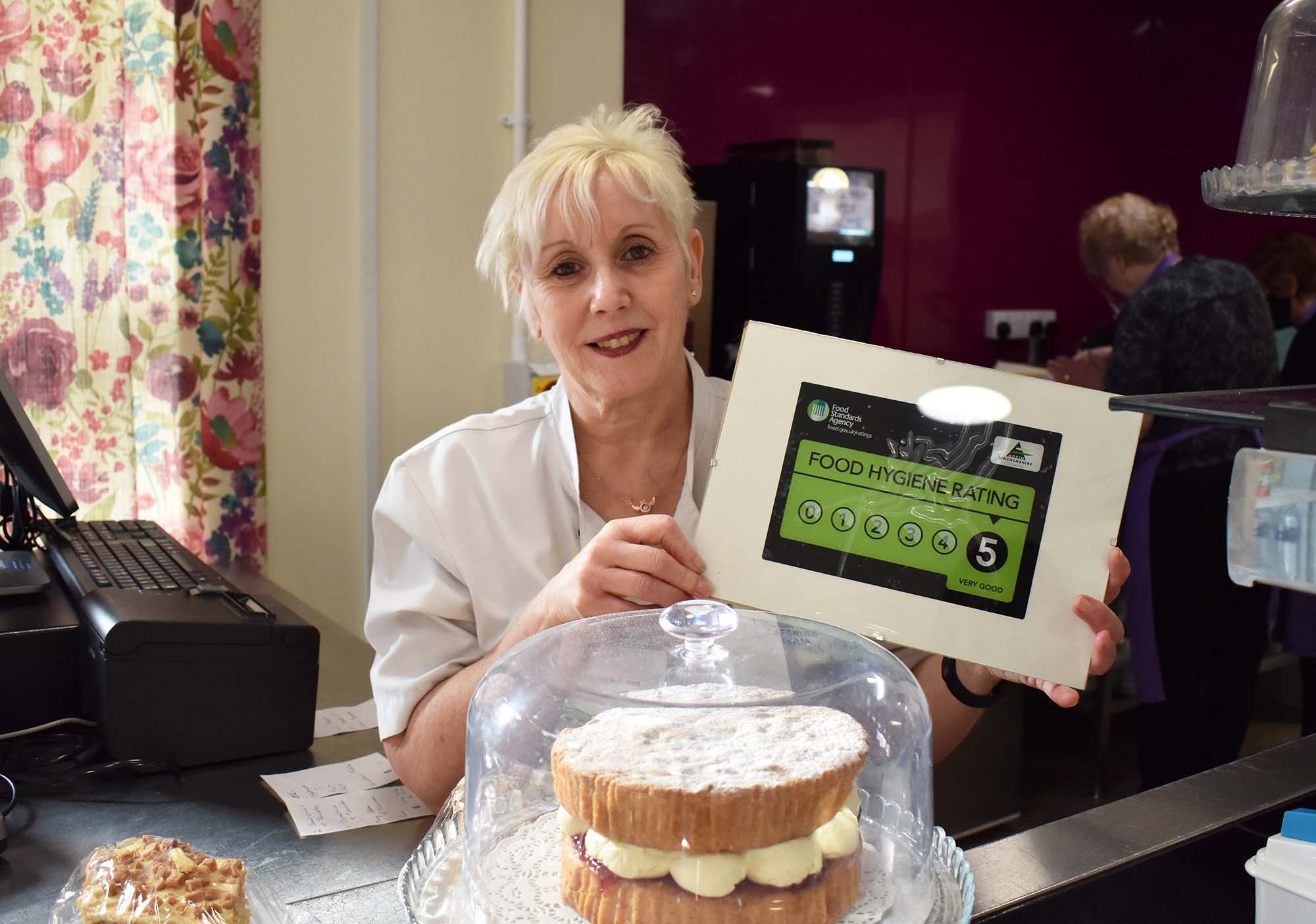 Jobs in catering. Picture shows a member of the lindsey lodge hospice catering team proudly displaying the 5 star food hygiene rating.